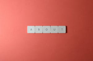 Close-up of keyboard buttons spelling 'ABOUT' against a red surface, minimalist style.